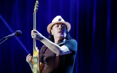 Carlos Santana z gitarą, gotowy do wykonania swoich niezapomnianych utworów.