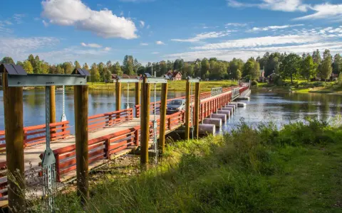 En bil kör över flottbron i Gagnef en solig dag.