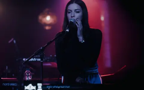 Wokalistka na tle sceny, przygotowująca się do występu na jednym z festiwali muzyki elektronicznej w Polsce.