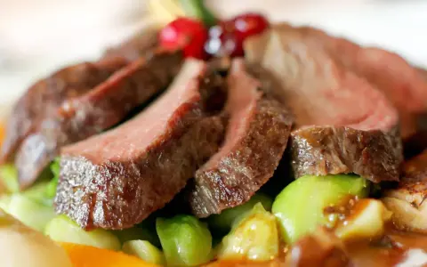 Saftiges Wildfleisch, zart geschnitten, mit knackigem Gemüse und Beeren garniert. Eine köstliche Antwort auf die Frage: Ist Wildfleisch gesund?