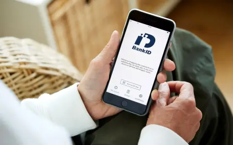 Person använder sin smartphone med BankID-appen för att logga in eller signera.