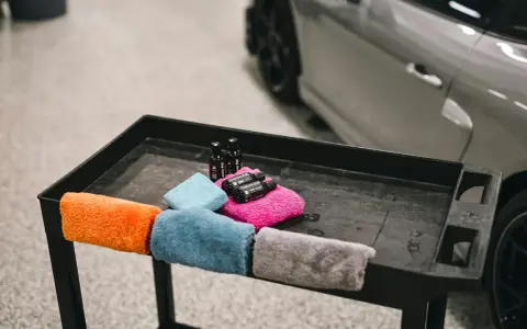 Kolorowe mikrofibry i buteleczki z preparatami do pielęgnacji auta. Tak prac mikrofibry, by auto lśniło.