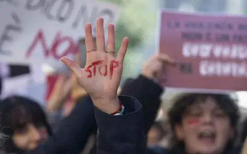 Mano alzata con "STOP" scritto in rosso, simbolo di protesta. Si evoca la necessità di una **codice rosso procedura** per proteggere le vittime.