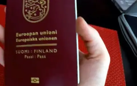 Dłoń trzyma paszport Finlandii. Czy do Finlandii trzeba mieć paszport? Tak, jeśli nie jesteś obywatelem UE/Schengen.