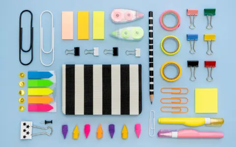 Un surtido vibrante de material de oficina lista para usar: clips, notas adhesivas, cintas, lápices y más, organizados sobre un fondo azul claro.