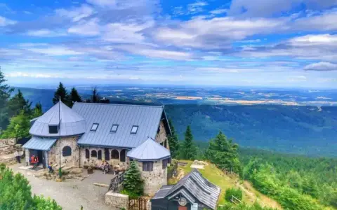 Kamienny schron turystyczny na tle rozległej panoramy Gór Izerskich. Wspaniałe widoki z górskich szlaków.