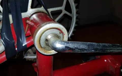 När man ska byta vevlager på cykeln syns en del av vevarmen och kedjekransen. Svart tejp håller ihop delar.