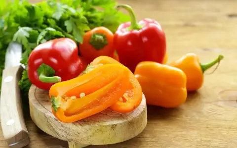 Peperoni piccoli colorati, pronti per gustose ricette. Un coltello e prezzemolo completano la scena.