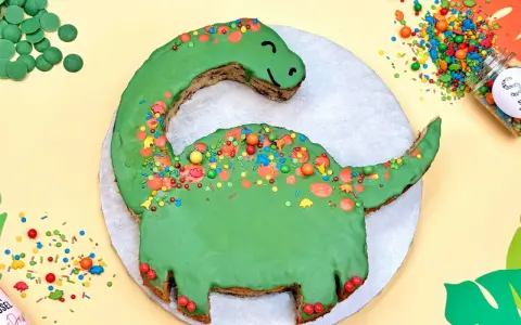 Grüne Dinosaurier Torte selber machen: Ein süßer Dino mit bunten Streuseln und Schokodrops. Perfekt für kleine Entdecker!