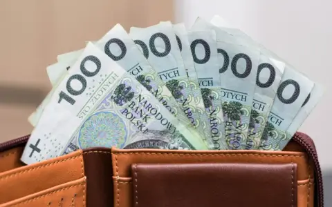Portfel z banknotami 100 zł. Czy urlop wychowawczy jest płatny? To pytanie nurtuje wielu rodziców, a pieniądze w portfelu mogą pomóc w podjęciu decyzji.