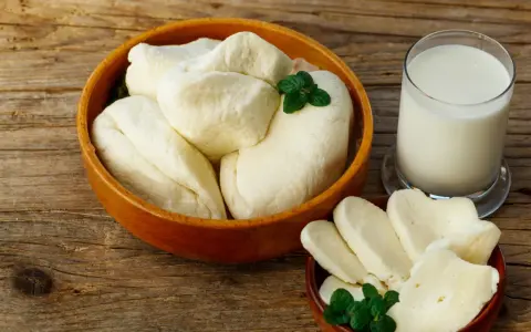 Ser halloumi w ciąży: świeży ser i szklanka mleka na drewnianym stole. Idealne dla przyszłej mamy.