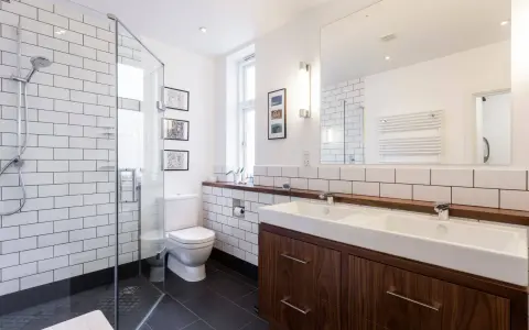 Baños modernos y reformados con plato de ducha, lavabo doble y mueble de madera.