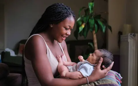 Eine junge Frau hält ihr Baby liebevoll im Arm. Die Frage "wie lange kann man stillen" beschäftigt viele Mütter.