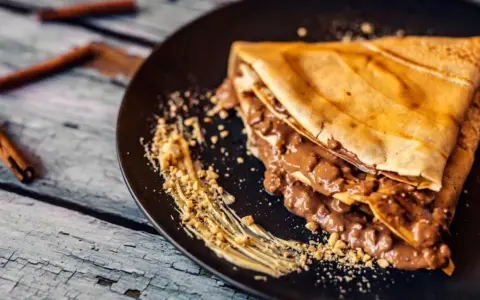 Crepe doblada con relleno cremoso de chocolate y trocitos de frutos secos. Una deliciosa receta crepes para disfrutar.