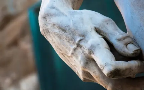 Main d'une statue de David à Florence, marbre patiné par le temps.