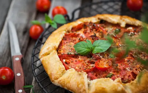 Torta salata con pomodorini freschi e basilico, pronta per essere gustata.