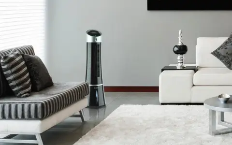 Ventilateur tour noir, solution pour la consommation clim mobile. Un salon moderne avec canapé et tapis blanc.