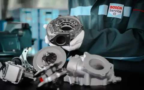 Mechanik w rękawiczkach prezentuje części turbosprężarki. Dowiedz się, ile kosztuje regeneracja turbiny w Bosch Service.