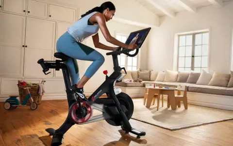 A woman rides a Peloton bike, a popular tool for peloton weight loss, in a bright, homey living room.