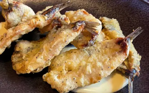 Crujientes boquerones fritos, dorados y servidos sobre una cremosa salsa.