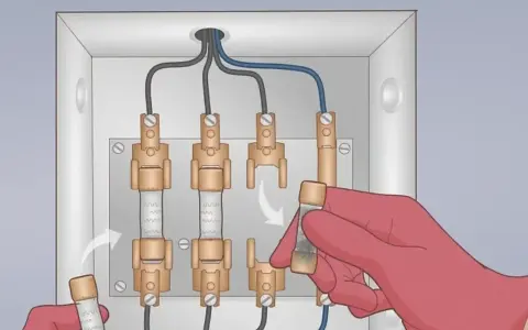 Main électrique avec fusibles. Une main gantée insère un fusible, illustrant le branchement d'un ampèremètre.