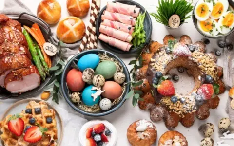 A festive Easter feast in Europe, featuring a glazed ham, colorful eggs, sweet breads, and a decorated cake.