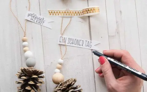 Déco Noël pomme de pin à faire soi-même : des suspensions naturelles avec perles en bois et messages personnalisés.