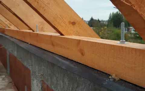 Murłata, czyli belka drewniana, mocowana do wieńca, stanowi podstawę konstrukcji dachu. Widać ją na tle nieba i drzew.