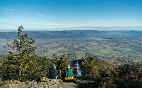 Rodzina podziwia widok ze Skrzycznego. Dziecko z rodzicami cieszy się panoramą Beskidów.