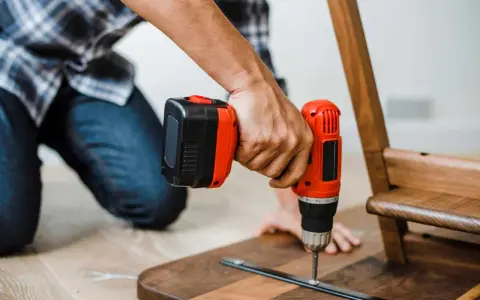 Un homme assemble un meuble en bois avec une perceuse. Un projet de bricolage maison réussi.