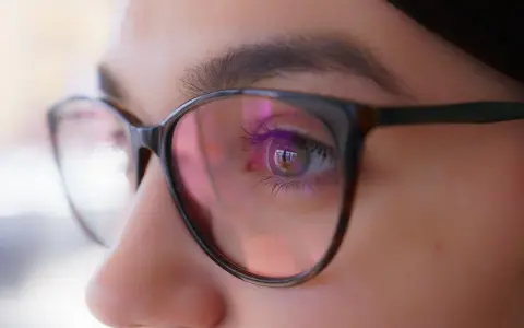 Zbliżenie oka w okularach, odbicie światła sugeruje, że optometrysta źle dobrane szkła.