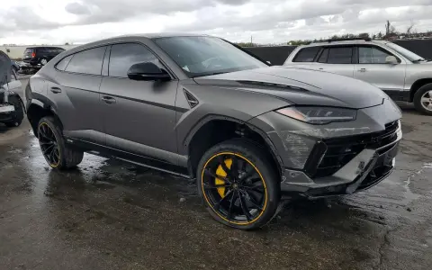 Szary Lamborghini Urus z żółtymi akcentami na felgach, uszkodzony z przodu. Zastanawiasz się nad lamborghini urus cena?