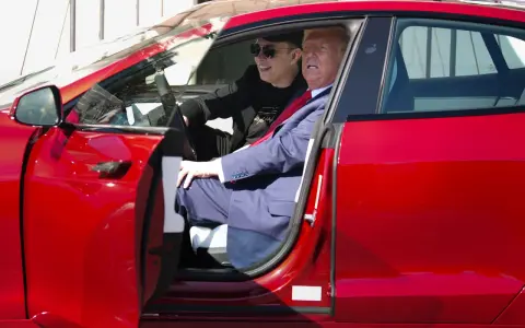 Elon Musk i Donald Trump siedzą w czerwonym samochodzie Tesla.