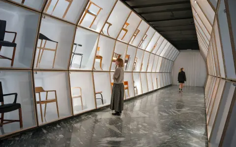 Wystawa krzeseł w muzeum designu Kopenhaga. Ludzie podziwiają ekspozycję w nowoczesnej, geometrycznej przestrzeni.