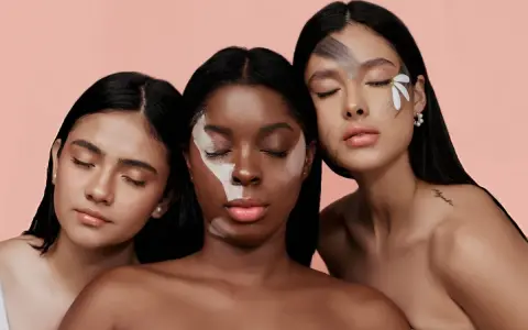 Tre donne con diverse tonalità di pelle, una con un trucco artistico sul viso, evocano la bellezza naturale e l'efficacia del palmitoyl tripeptide-1.