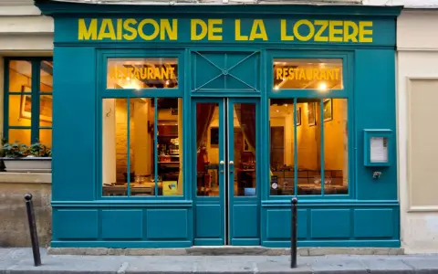 Maison de la Lozère, un ristorante accogliente dove mangiare a Parigi. L'insegna gialla risalta sulla facciata turchese.