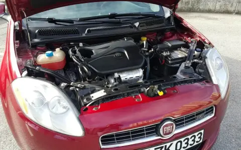Czerwony Fiat Bravo 1.4 T-Jet z otwartą maską, widoczny silnik i reflektor.