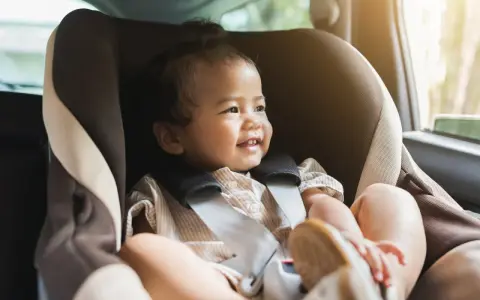 Glückliches Kleinkind im Kindersitz, bereit für eine Fahrt. Ein reboarder test zeigt, wie sicher es ist.
