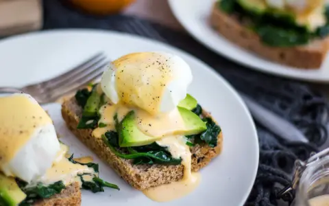 Pyszne jajka po florencku na tostach z awokado i szpinakiem, polane sosem holenderskim. Idealne na brunch!
