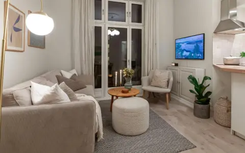 Salon cosy avec canapé, fauteuil, table basse et pouf. Une astuce rangement petit appartement : le meuble bas sous la TV optimise l'espace.