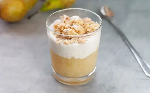 Ein Glas mit Birnenkompott, Sahne und Streuseln. Perfekt, wenn man etwas Süßes sucht, das gut zu Birnenkompott passt.