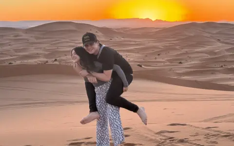 Jóvenes disfrutando de un atardecer en las dunas de Marruecos con niños.