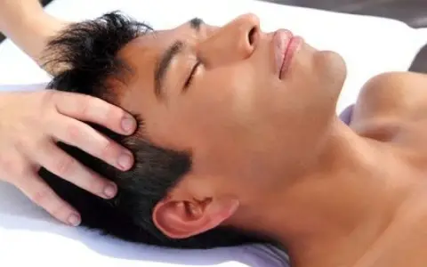 Un homme se fait masser le cuir chevelu tous les jours pour se détendre. Ses yeux sont fermés, profitant de ce moment de bien-être.
