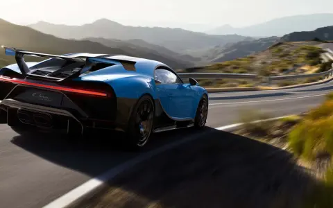 Blauer Bugatti Chiron Pur Sport rast auf einer kurvigen Bergstraße.