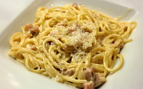 Pyszne spaghetti carbonara z kawałkami boczku, posypane parmezanem. Idealny wybór, jaki boczek do carbonary.