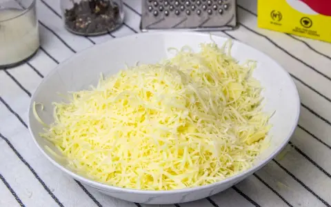 Queso rallado en un bol blanco, listo para hacer fondue.