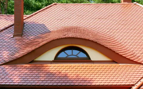 Ceglana dachówka ceramiczna w kształcie rybiej łuski, z ozdobnym lukarną. Idealna, by stworzyć stylowy dach.