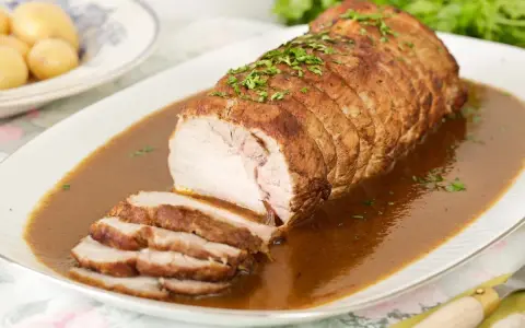 Lomo de cerdo al horno en papel aluminio, jugoso y tierno, bañado en salsa y espolvoreado con perejil.