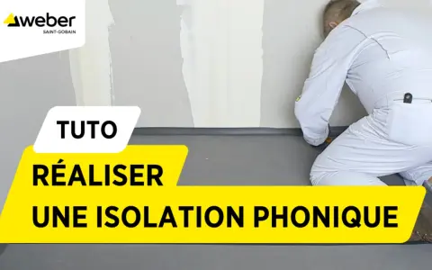 Tuto : réaliser une isolation phonique sur carrelage existant. Un ouvrier en combinaison blanche installe un revêtement gris au sol.