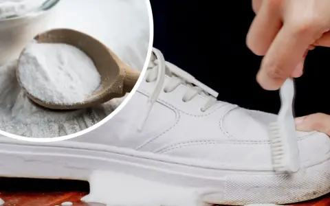 Białe trampki czyszczone szczoteczką z użyciem sody do butów. W tle drewniana łyżka pełna białego proszku.